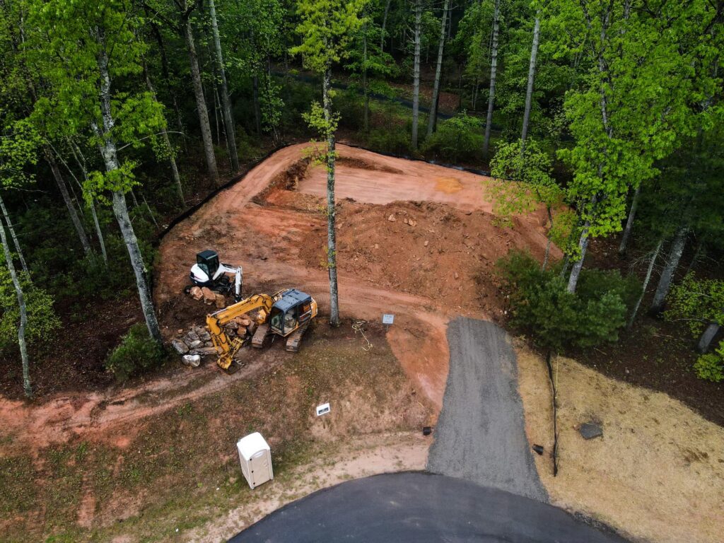 Heavy construction equipment around a graded pad for a home site